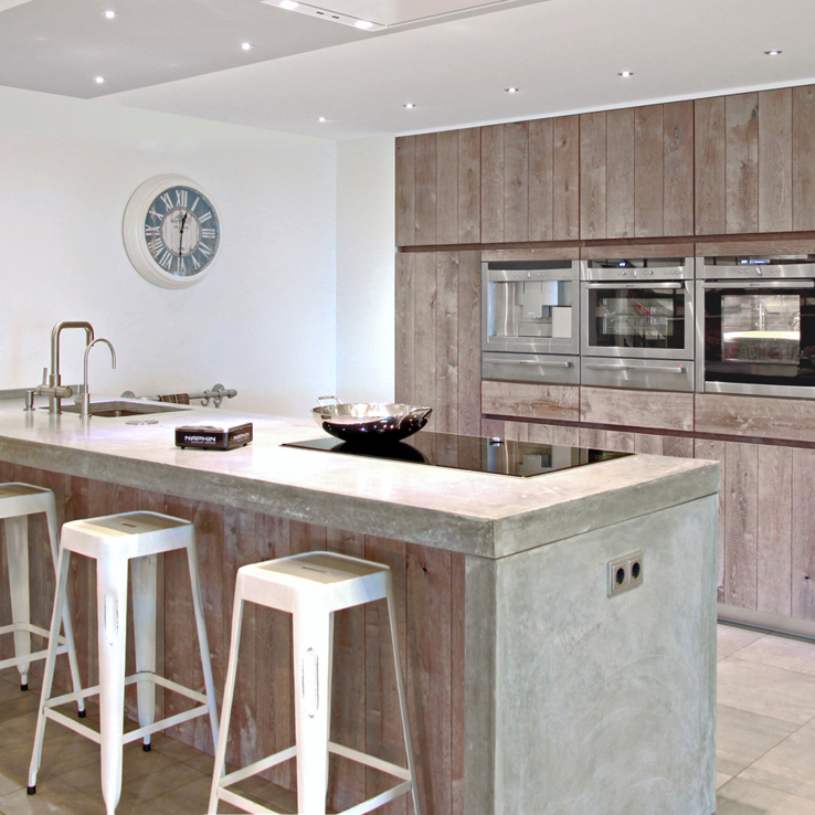 Luxe keuken met betonnen aanrechtblad. Losse kastenwand en bargedeelte.